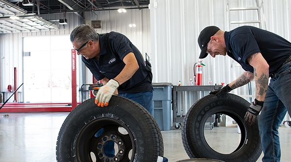 Two mechanics inspecting tires