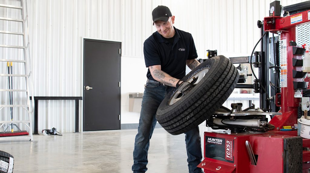 Worker lifting tire into machine